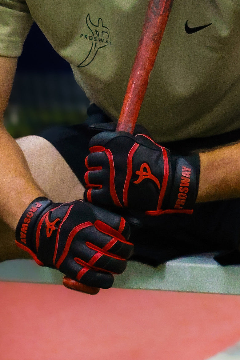 Black and red ProSway batting gloves gripping a bat